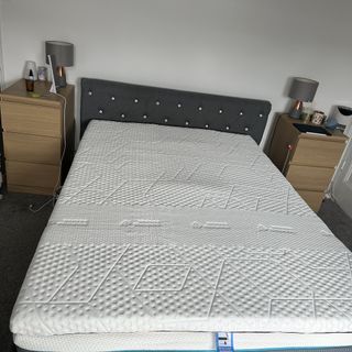 The Emma Premium mattress topper on a grey upholstered bed