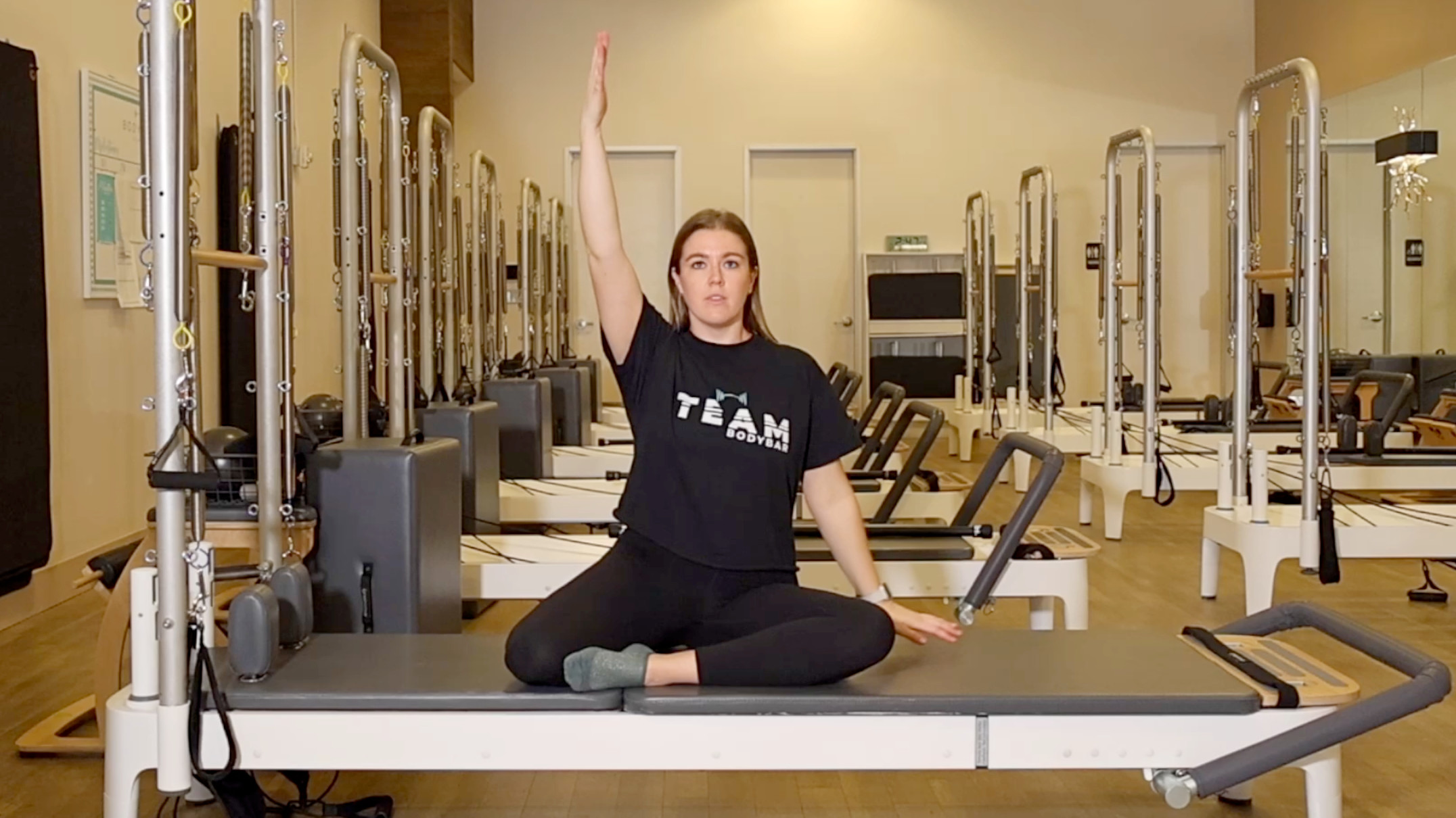Woman demonstrating a Pilates exercise on the carriage of a Pilates reformer machine