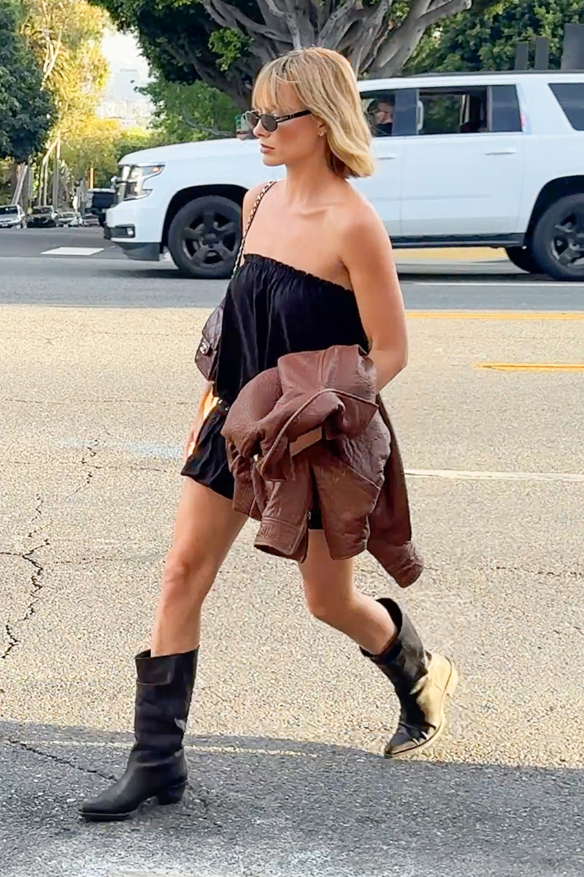 Margot Robbie wearing a black strapless mini dress with Khaite Western boots.
