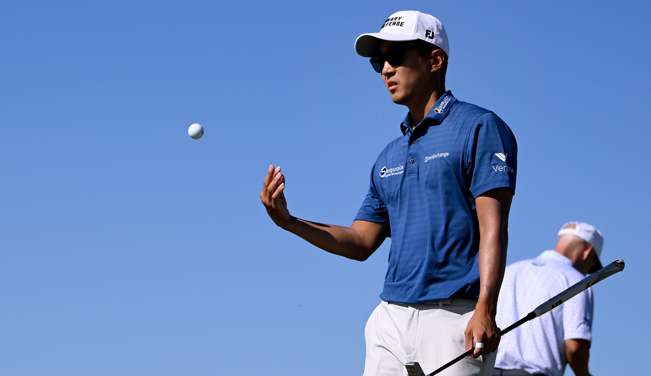 Michael Kim throws a golf ball to his caddie