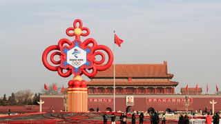 Tourists look at a giant Winter Olympics landmark under construction at Tiananmen Square on January 14, 2022 in Beijing, China. Elements of the 2022 Winter Olympics are combined with those of traditional culture to greet the Chinese New Year.