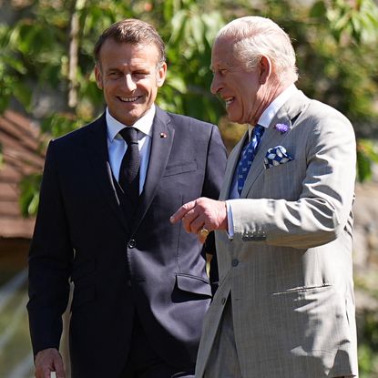 King Charles and Emmanuel Macron laughing in suits outside