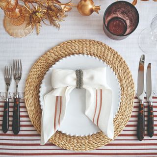 A dinner table set up for a Christmas meal with a bow-shaped napkin on the plate