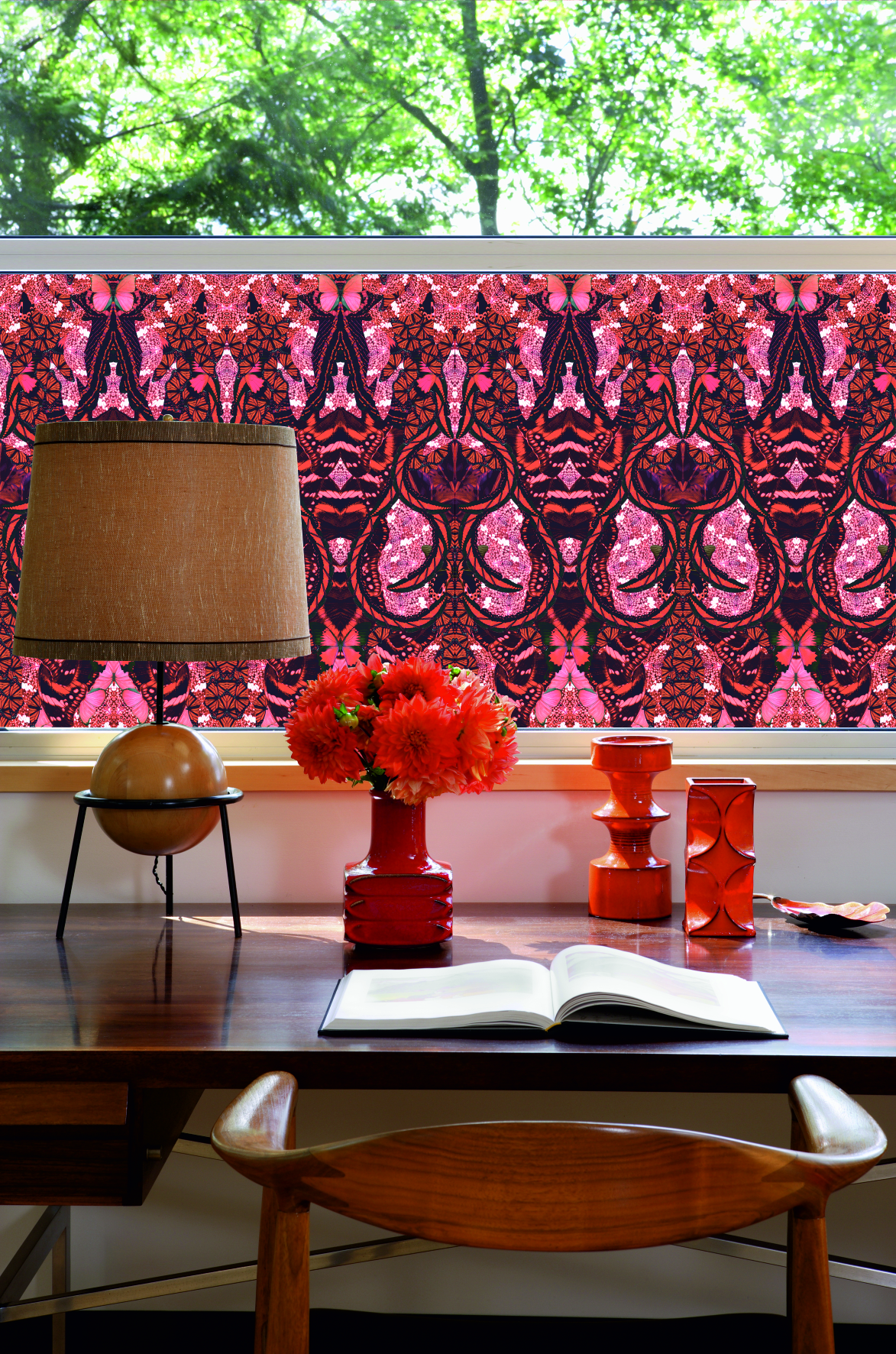 desk space with bright floral window film, a large lamp, and red decorative glass vases