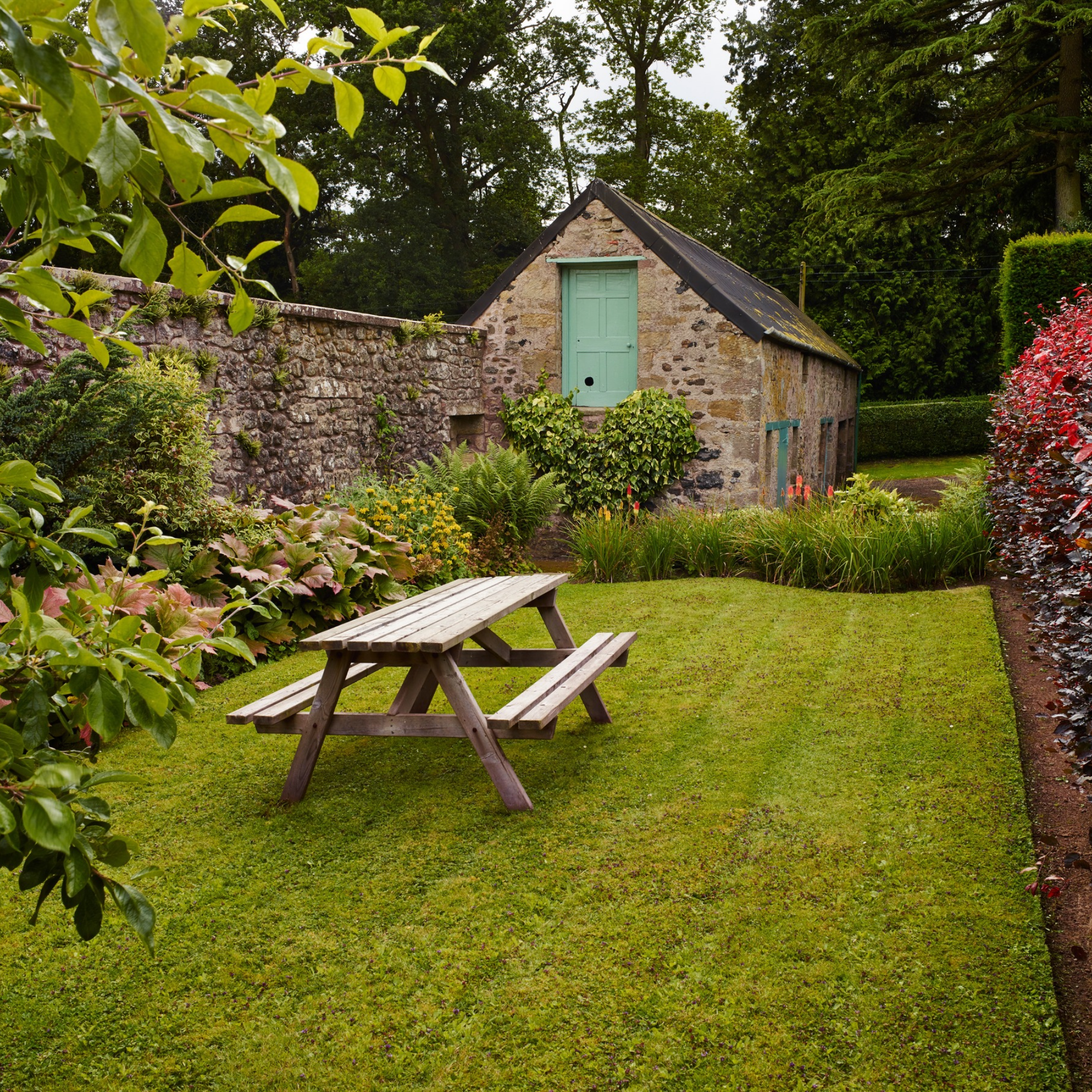Flower and plant beds. Lawn, table and benches.