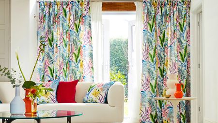 A living room with cream-colored upholstered sofa and multicolored bright botanical motif curtain decor