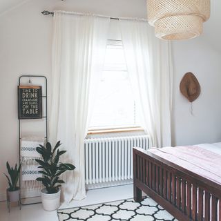 Bedroom with a bed, geometric rug and a rattan lampshade