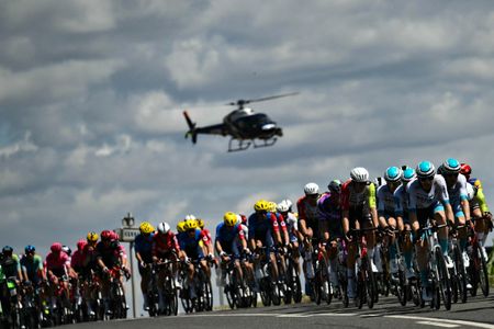 A helicopter hovers over the peloton during the 2025 Tour de France