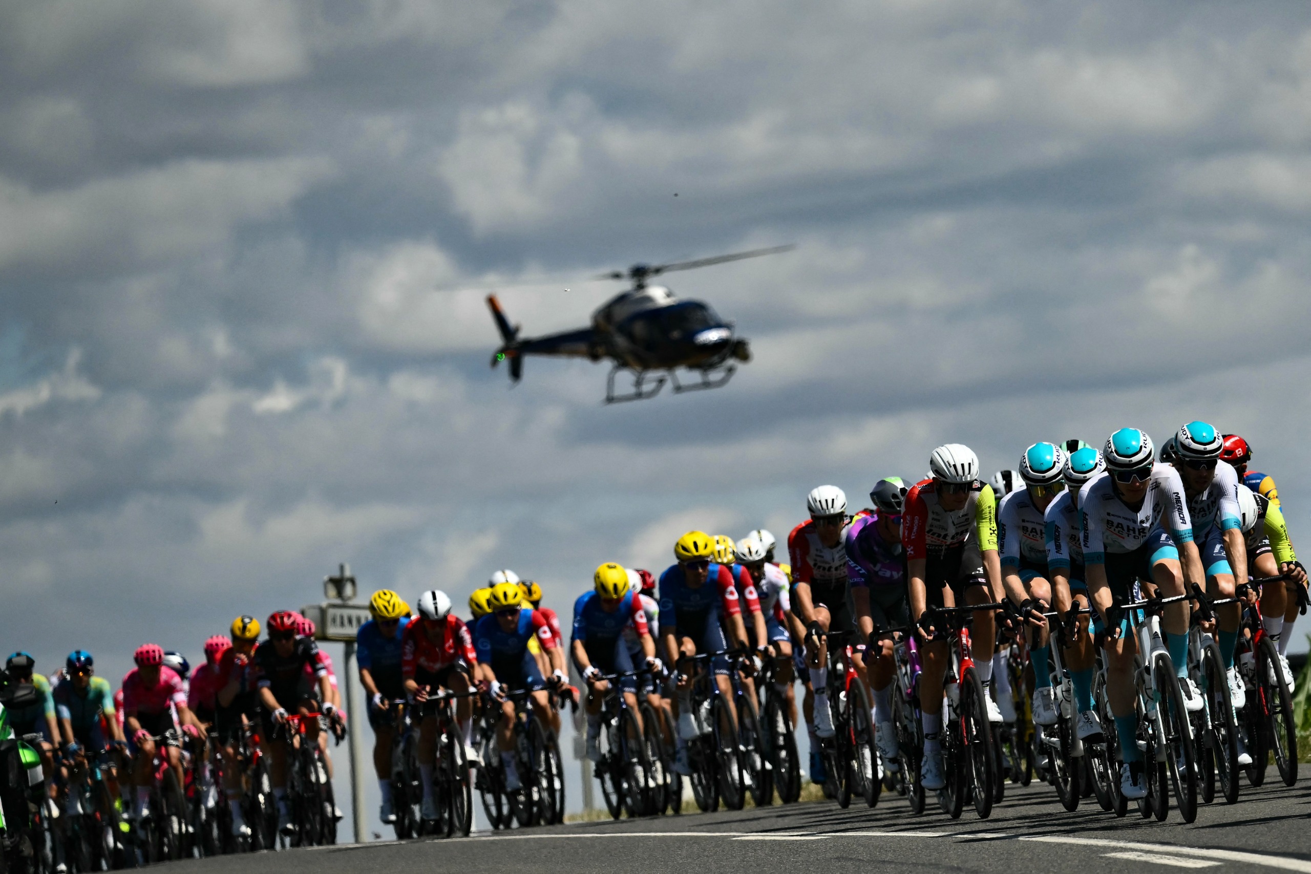A helicopter hovers over the peloton during the 2025 Tour de France
