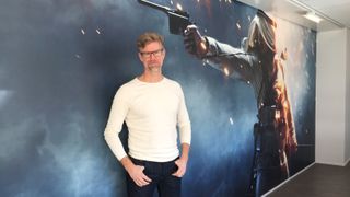 Lars Gustavsson stands in front of a large piece of artwork from Battlefield 1.