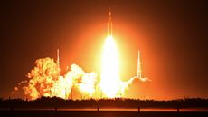 Photo of a stream of orange fire coming from the Artemis I rocket as it launched into space at night