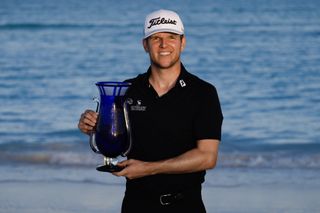 Jeremy Paul holds the Bahamas Great Exuma Classic trophy on the beach in 2024