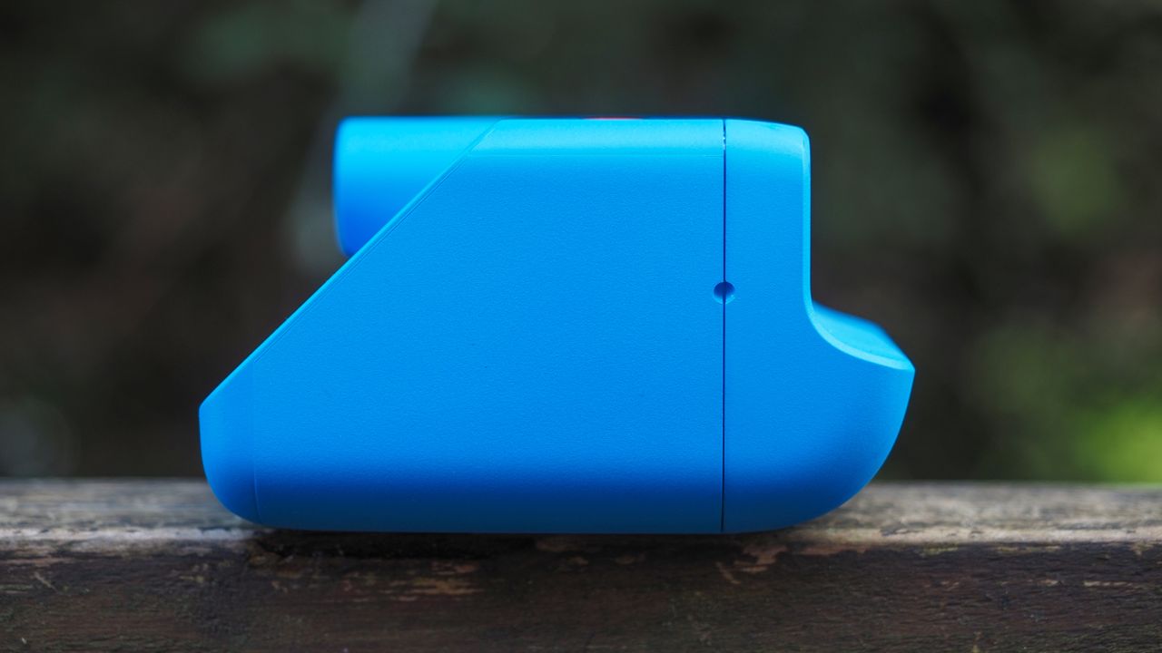 Blue Polaroid Go Gen 2 camera, on a wooden surface in a woodland setting