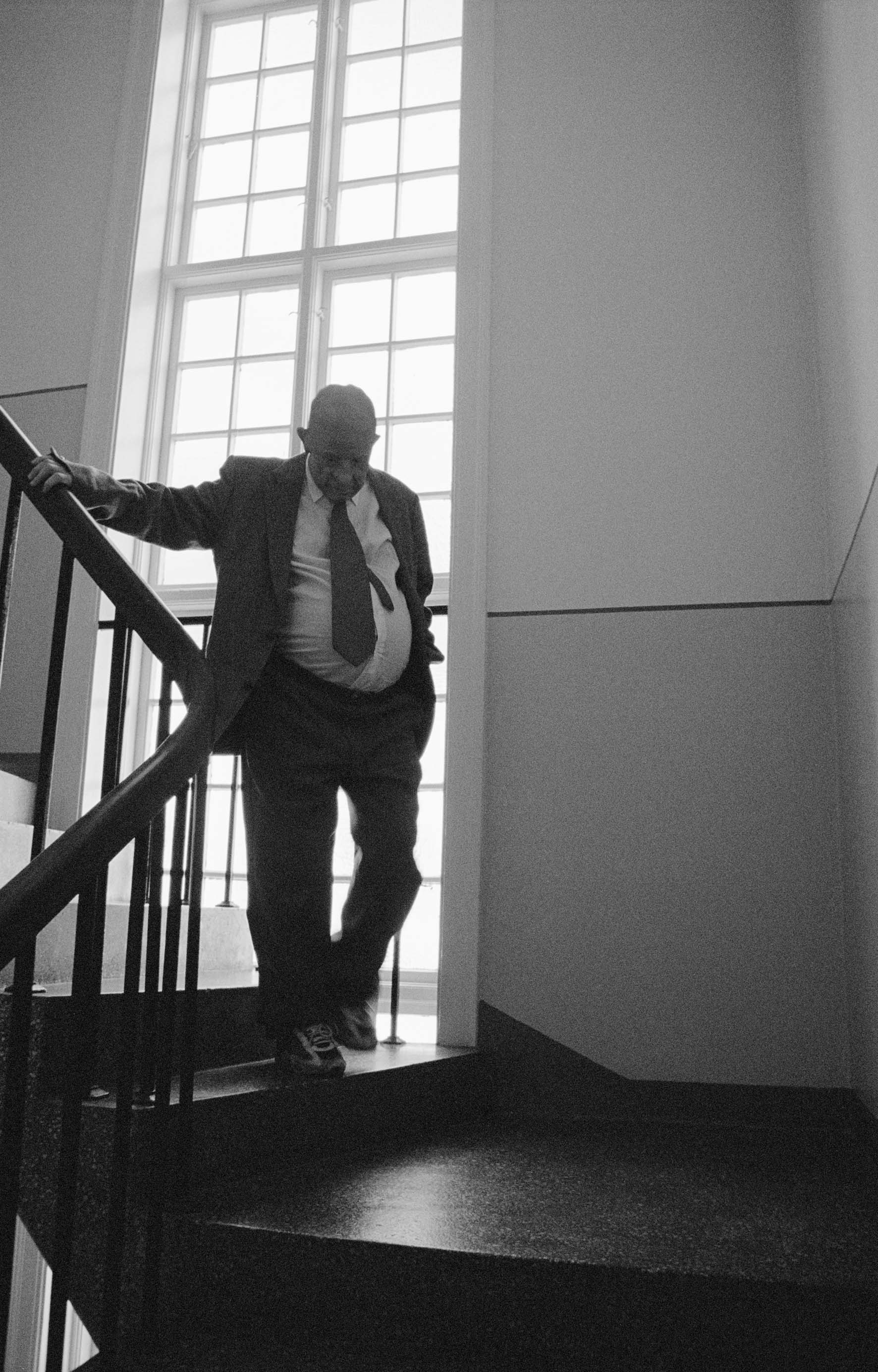 photograph of old man with paunch descending stairs