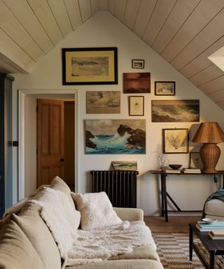 shiplap vaulted ceiling in a cozy beach house living room with rattan lamp and sea paintings