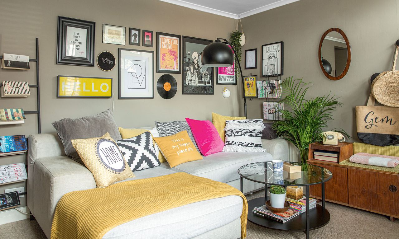 Grey living room with white chaise sofa, gallery wall, black arc lamp, ladder shelf and glass coffee table