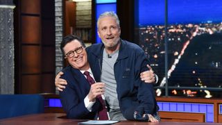 Jon Stewart sitting on Stephen Colbert's lap on The Late Show with Stephen Colbert