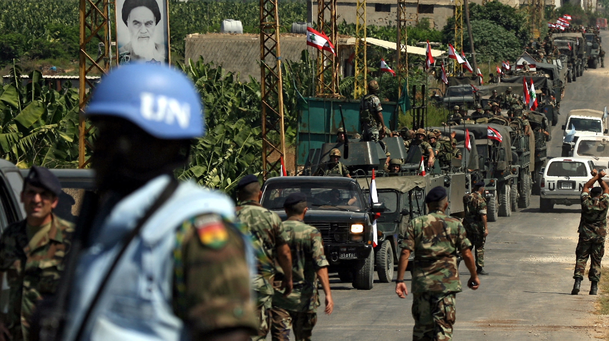 TOPSHOT - A convoy of Lebanese army military vehicles drive past a portrait of the late leader of Iran's Islamic revolution, Ayatollah Ruhollah Khomeini, at a UN checkpoint manned by Ghanaian peacekeeping forces in the coastal southern Lebanese city of Tyre, 08 September 2006. The UN Interim Force in Lebanon (UNIFIL) is tasked with enforcing a fragile truce between Israel and Hezbollah militants, and supporting the Lebanese army as it takes up positions in southern Lebanon. 