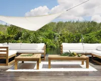 A white outdoor rug on wooden decking with contemporary white upholstered garden furniture 