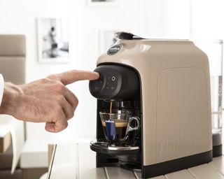 A man pressing a Lavazza Idola coffee machine button demonstrating how to use a coffee maker
