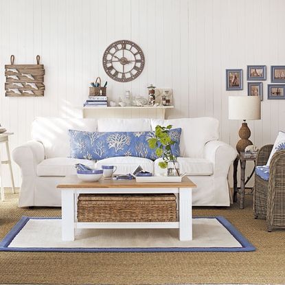 living room with white walls carpet on flooring and sofa set with cushions