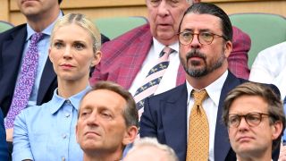 Dave Grohl and wife Jordyn Blum look serious as they watch Wimbledon 2024. 