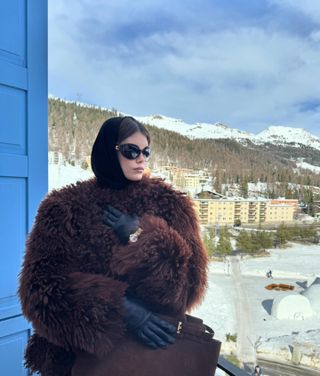 Kaia Gerber wearing a fur coat and Omega watch