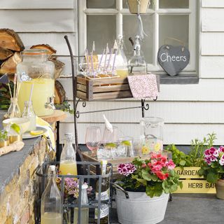 Ad hoc outdoor bar on planter with glasses, jugs and drinks dispenser