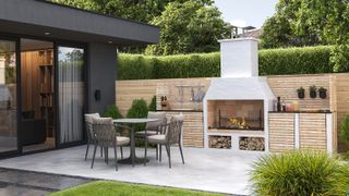 An outdoor fireplace built in to an outdoor kitchen area on a patio 
