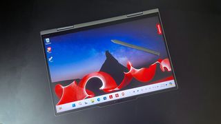 The Lenovo ThinkPad X1 2-in-1 Gen 9 folded in tablet mode sitting on a black desk with a stylus on top