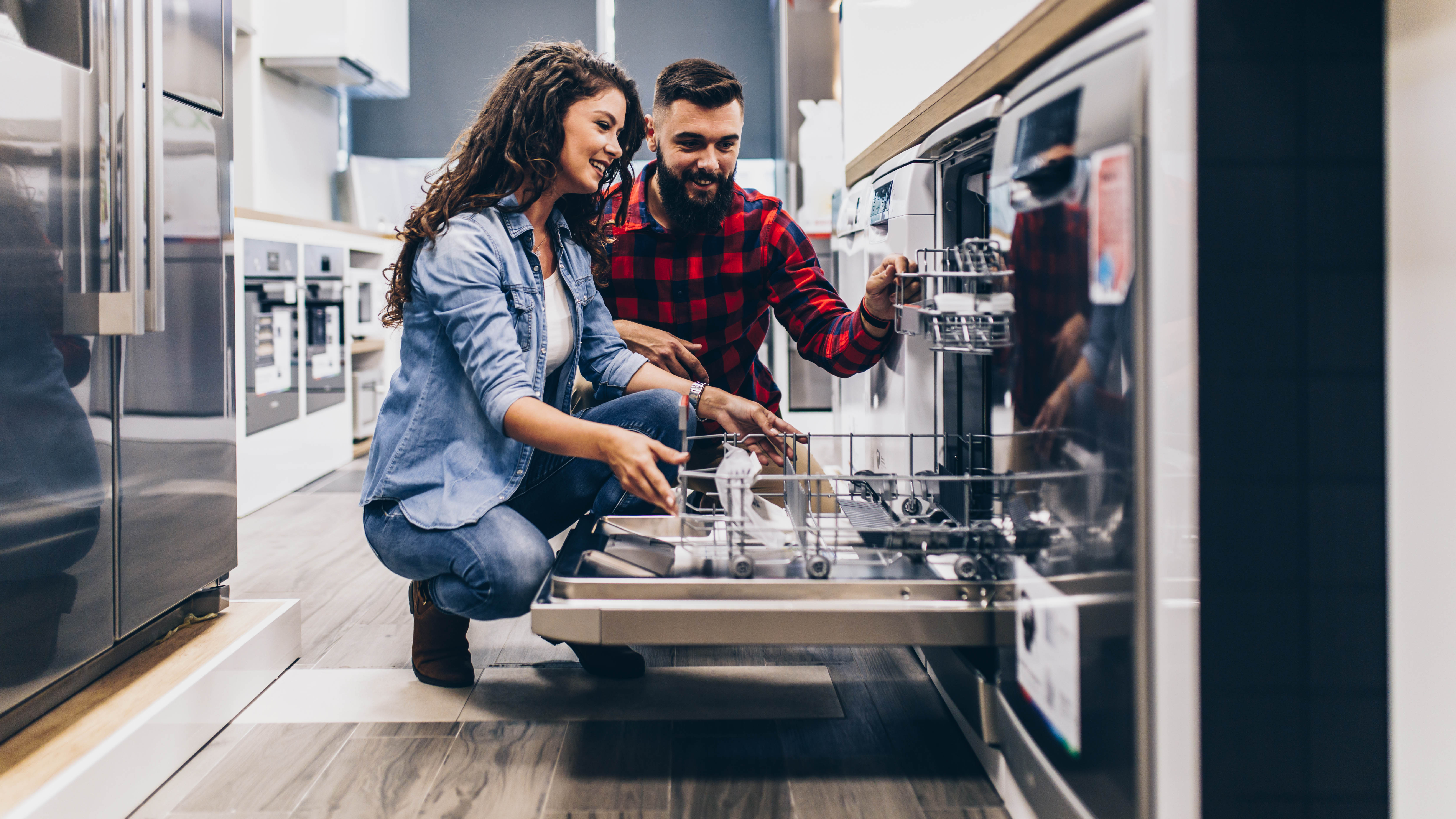 Couple looking inside a dishwasher in store