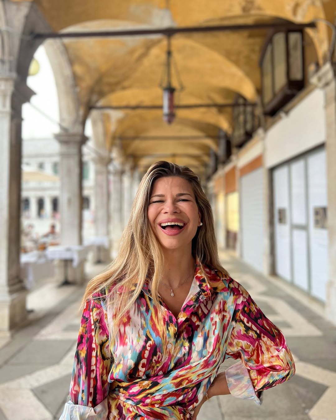 A woman with blonde hair smiling in a hallway