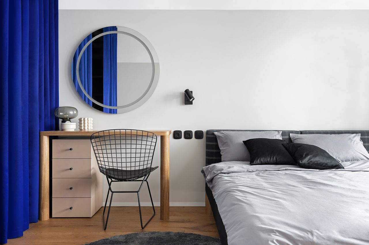A white toned bedroom with a deep blue curtains
