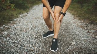 How to exercise without hurting your knees: Man holding knee in pain while outside