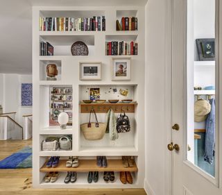 Custom wall with built-in bookcase shelves, space for shoes, and pegs to hang clothes