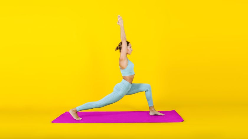 Woman holding a lunge while on a pink exercise mat in a bright yellow room