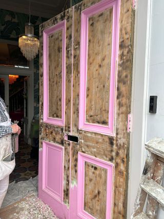 The Georgian homes front door being painted pink, which has a plasterboard underneath