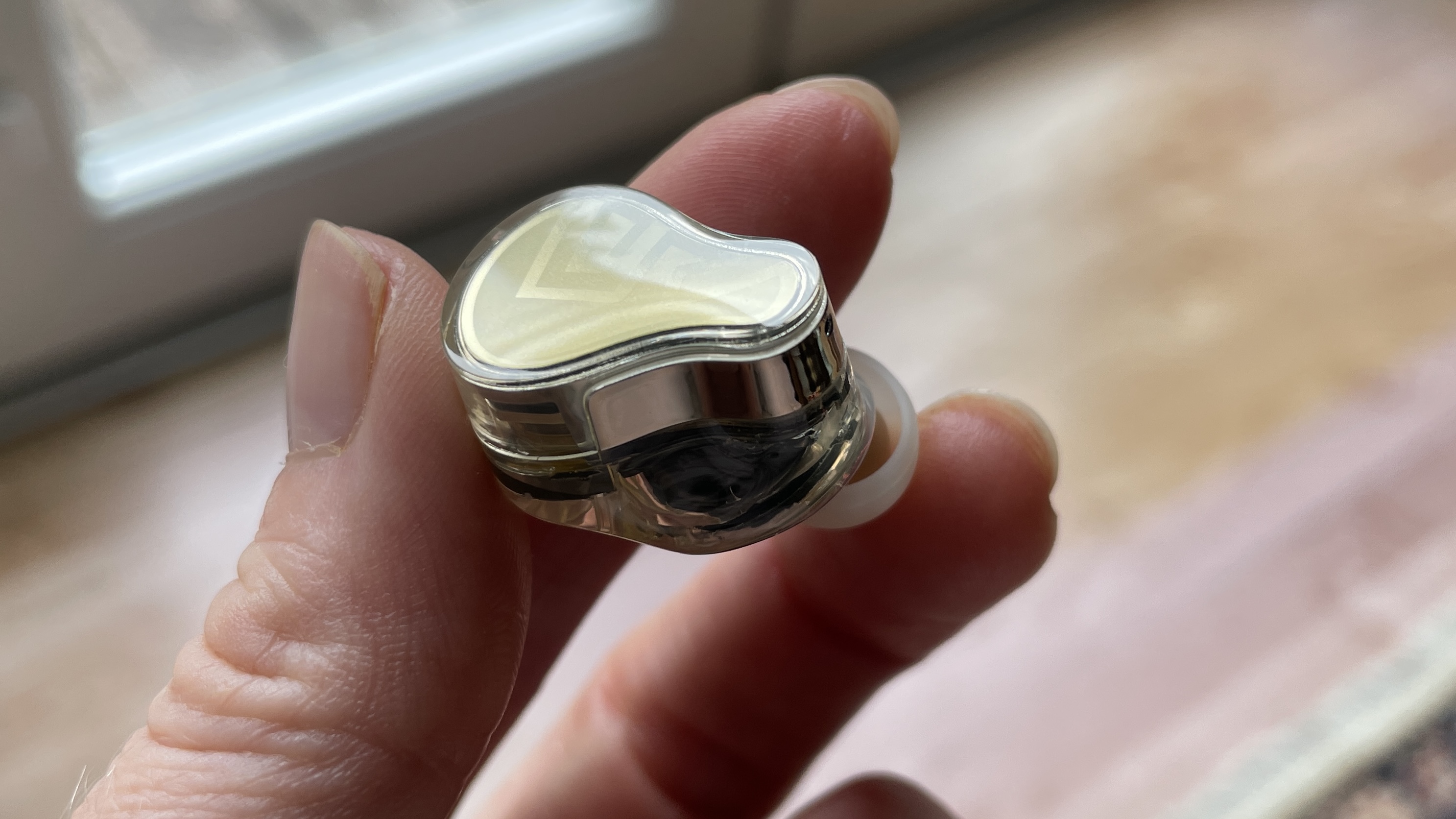 SoundPeats H3 earbuds and case held in a hand, in a living room
