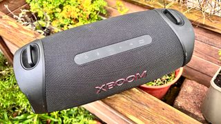 LG XBoom Go XG8T wireless speaker on wooden garden bench