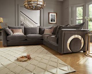 A grey velvet sofa with chrome insert detail and statement living room light ceiling fixture