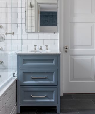 A bathroom backsplash idea with white subway tiles and a blue single vanity