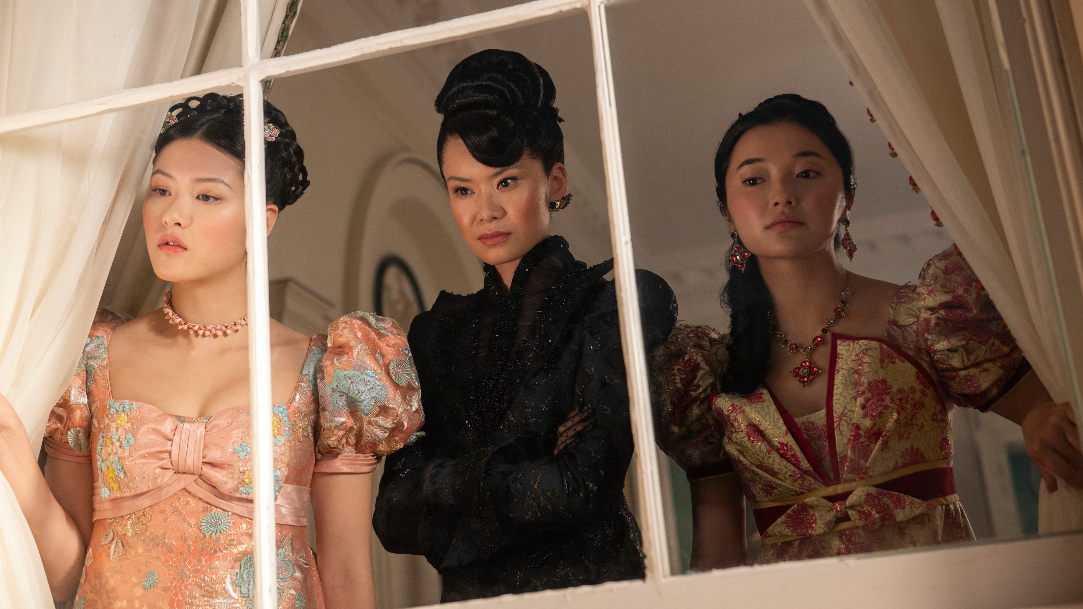 (L to R) Isabella Wei as Posy Li, Katie Leung as Lady Araminta Gun, Michelle Mao as Rosamund Li look through a window in a still from "Bridgerton" season 4
