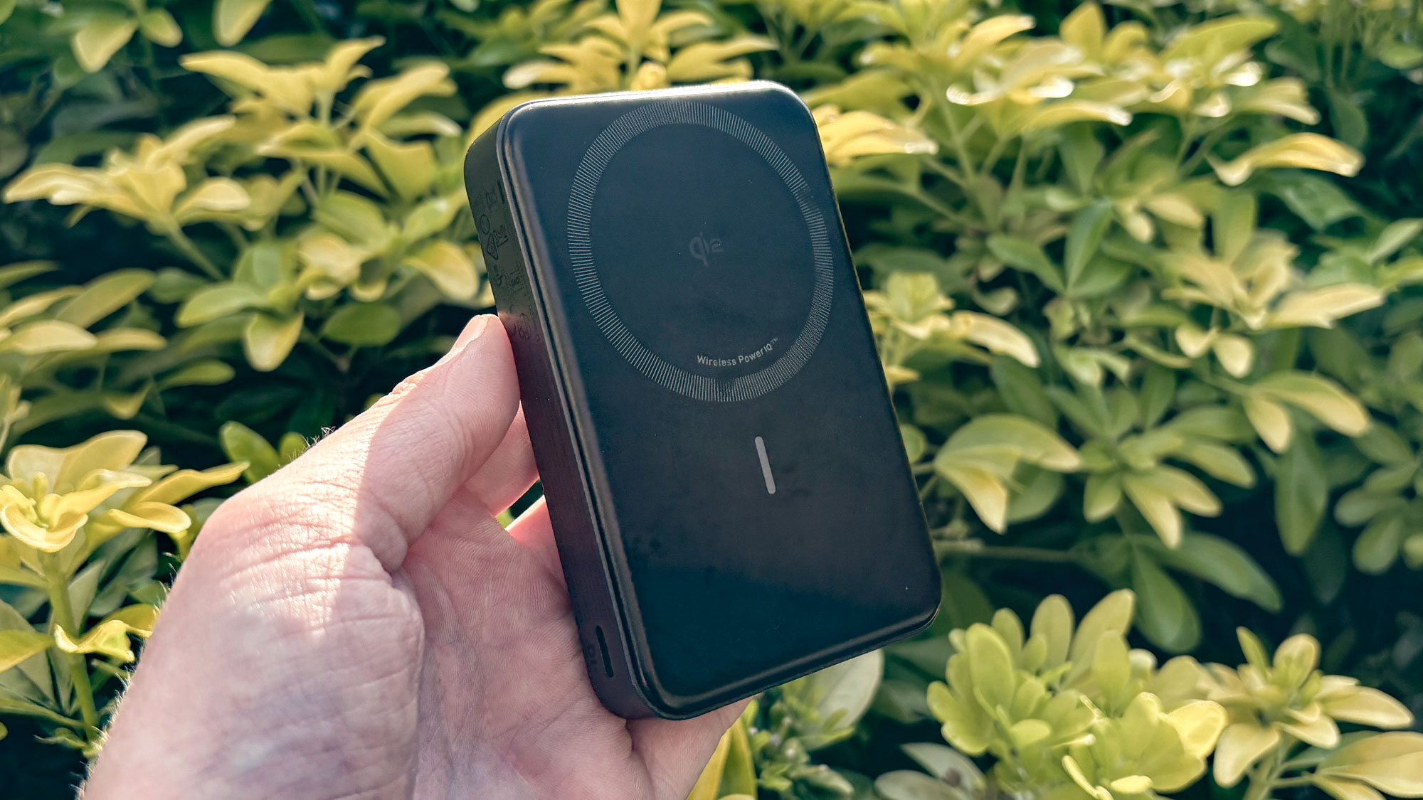 Anker MagGo Power Bank held in hand with bush in the background