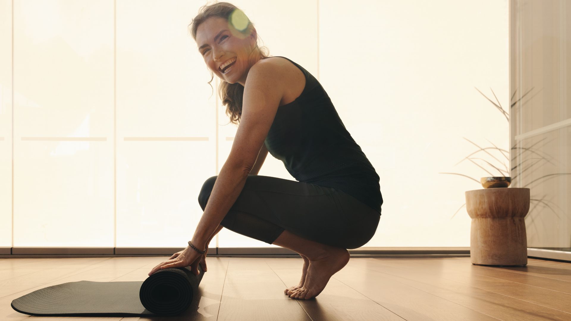 Woman doing heel touches exercise, rolling out yoga mat in studio
