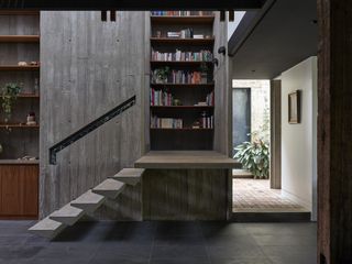 concrete interior and bookshelves at Stockroom Cottage by Architects EAT