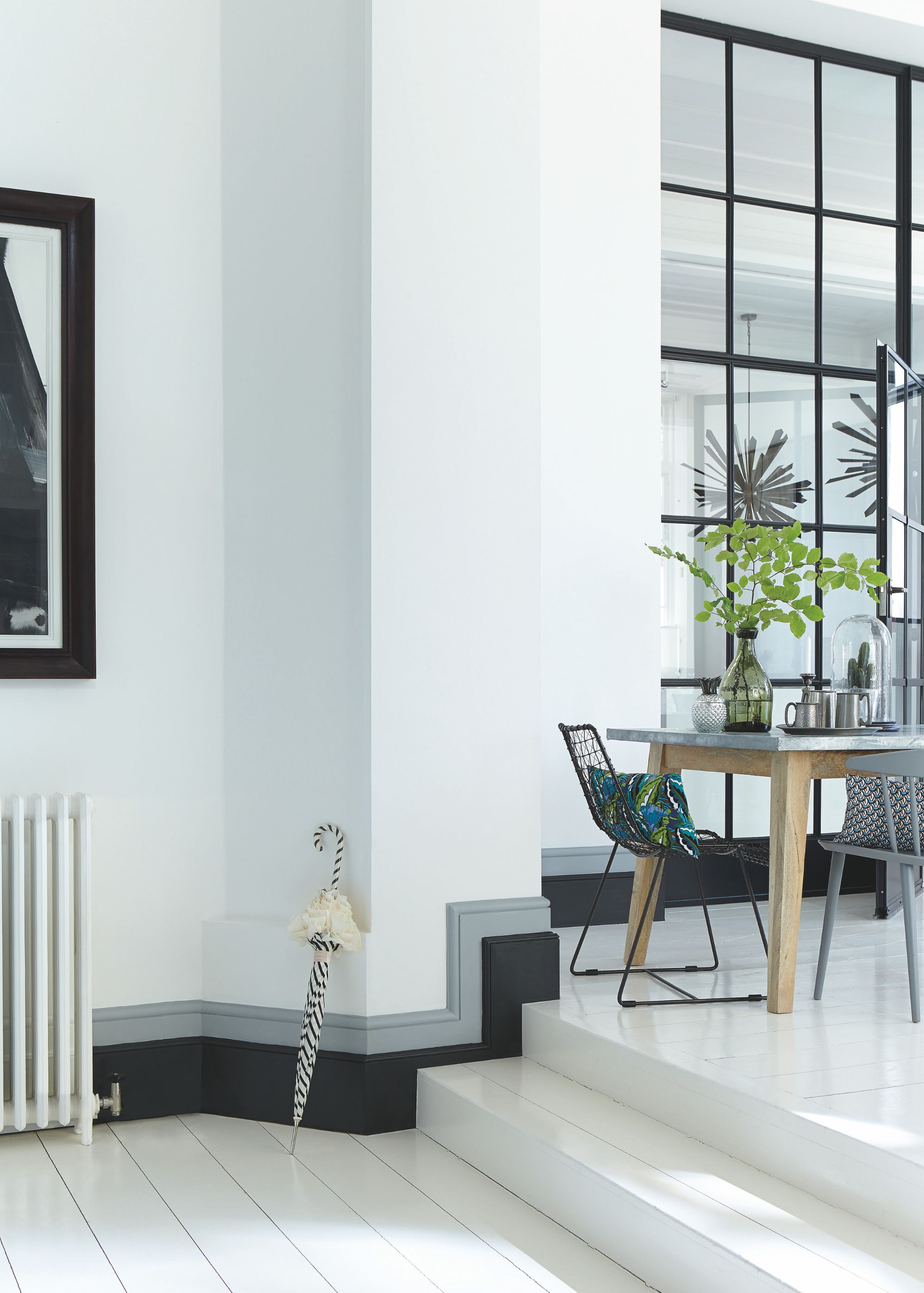 A white hallway with black trim, white wooden floors and a mirrored wall.