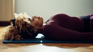 Woman lying down on a camping mat on wooden floor