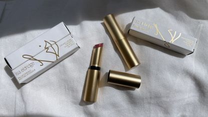 the Lisa Eldridge Baume Embrace Melting Lip Colour balms in their packaging on a linen sheet