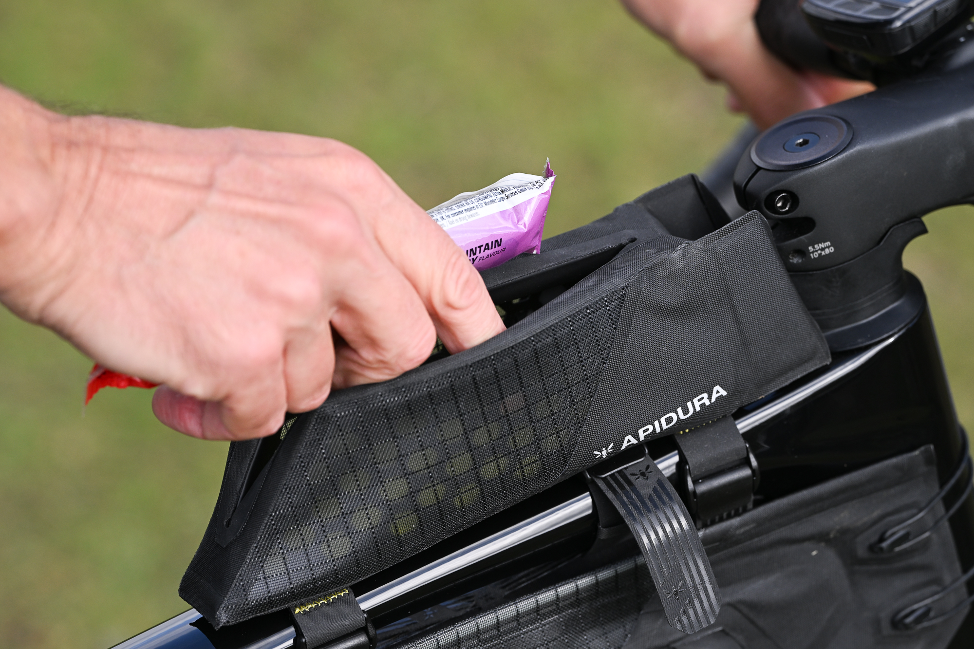 close up of a man putting a packet of Shot Bloks into a black top tube bag