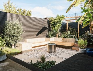 A backyard that makes use of natural materials with pebble gravel and a bench made from granite
